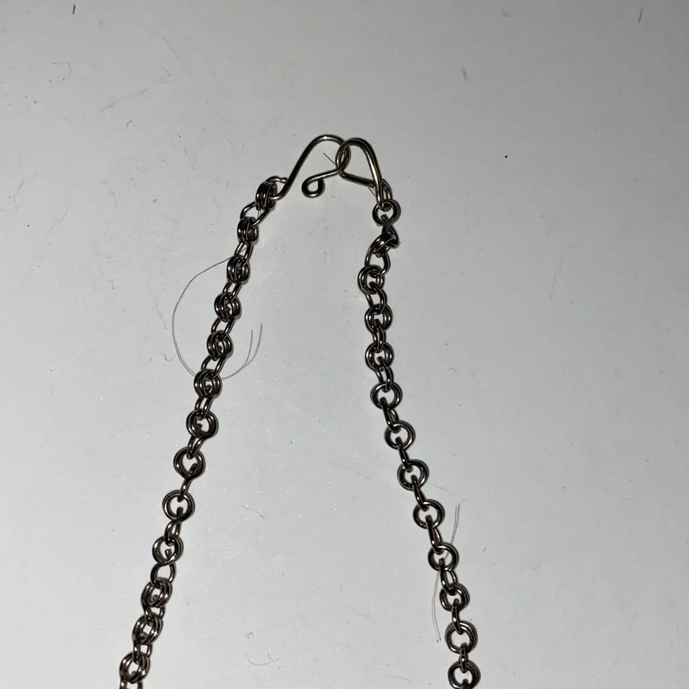Ornate Silver-Toned Necklace with a Curved Center Adorned with Blue/Black Stones
